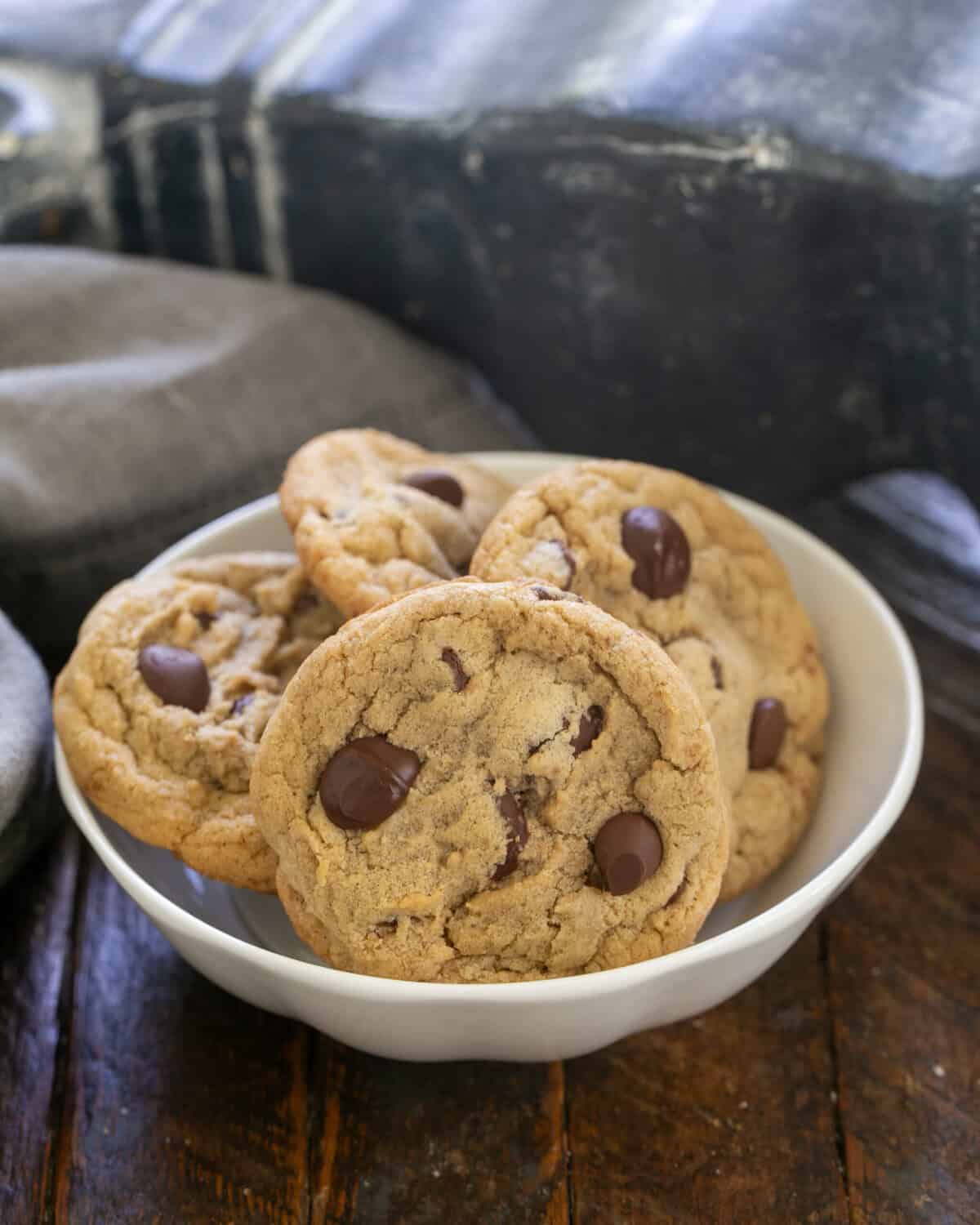 4 killer chocolate chip cookies in a white bowl.