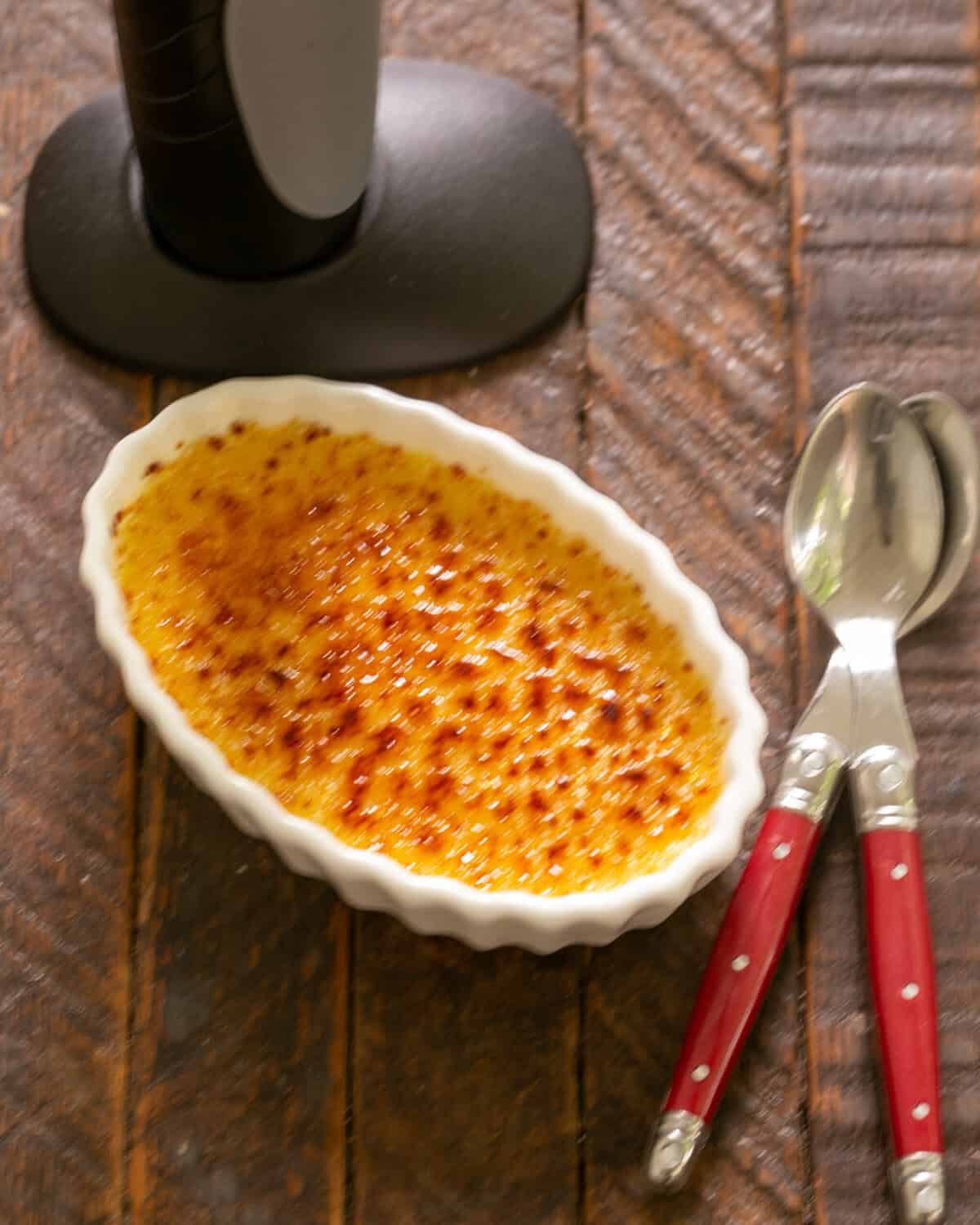 Finished creme brulee with 2 red handle spoons.