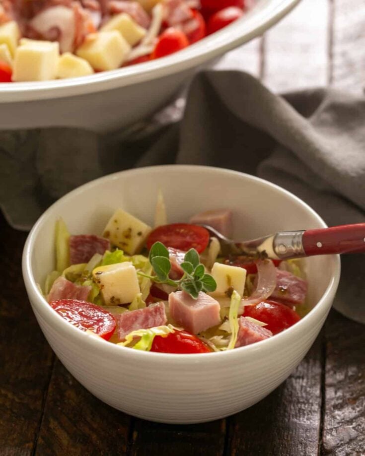 Italian chopped salad in a small bowl with a red handled spoon.