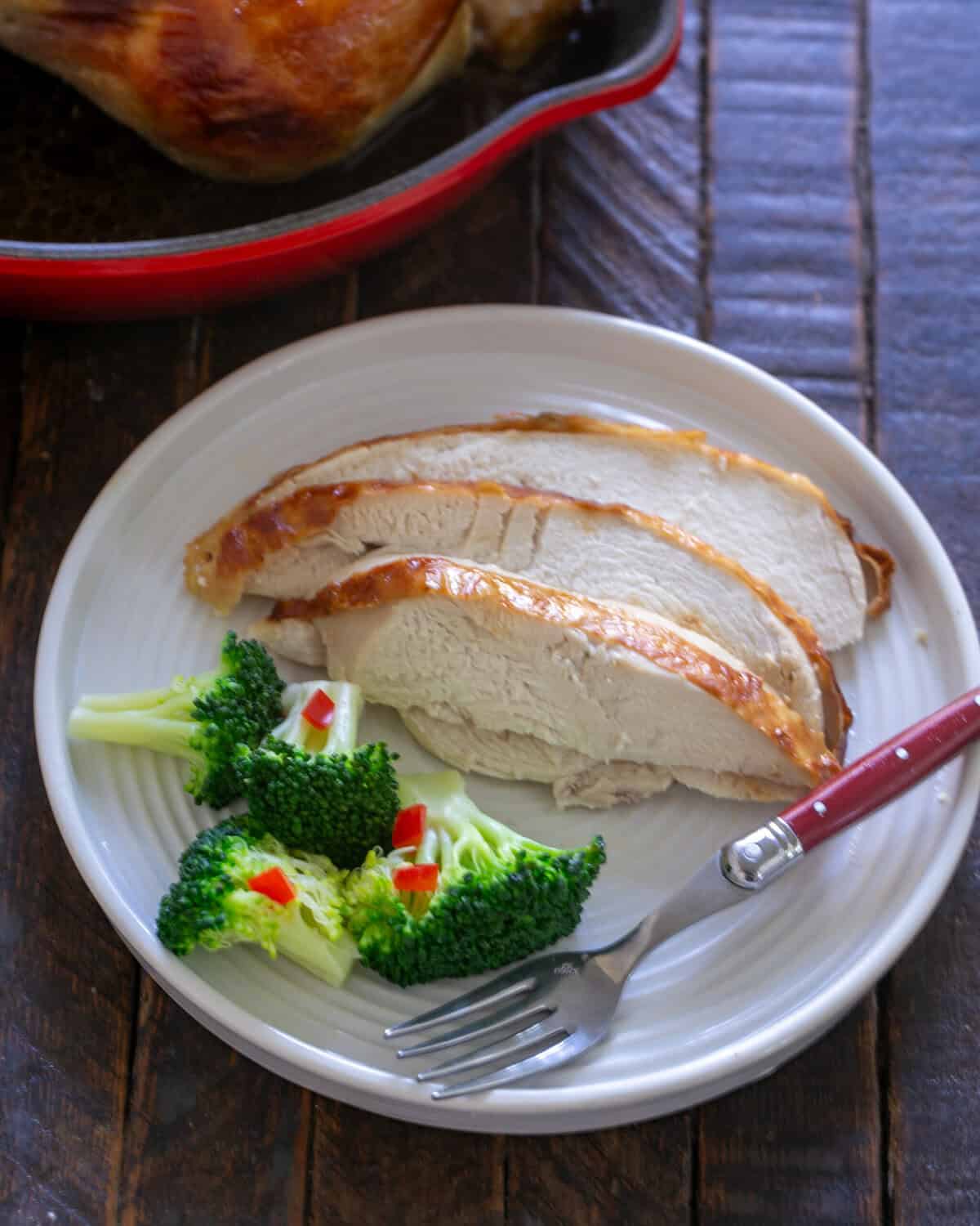 Buttermilk chicken sliced on a plate in front of roasting pan.