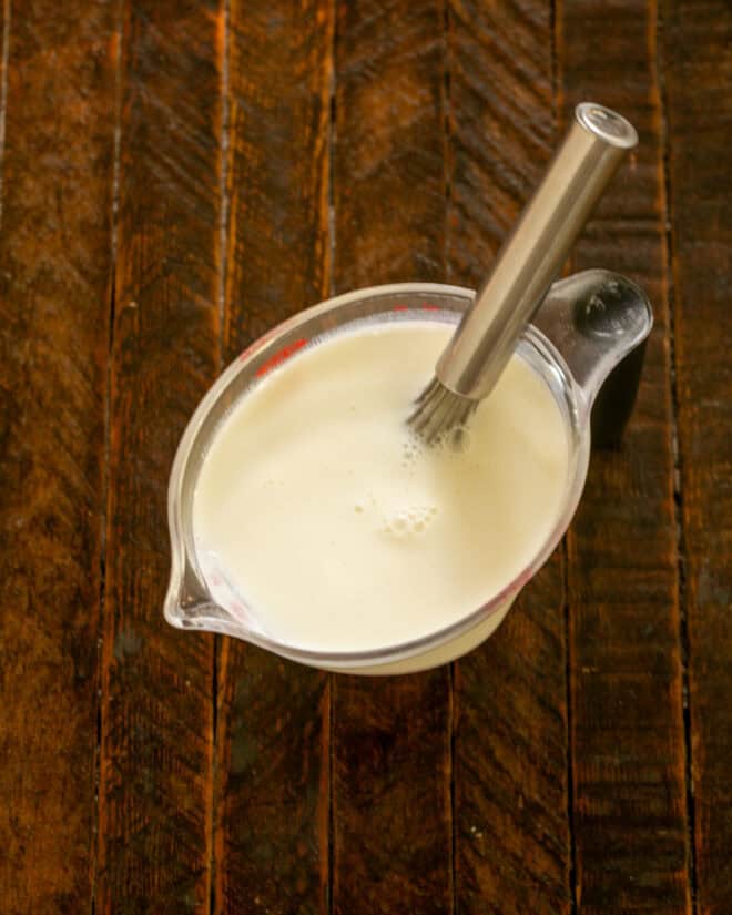 Buttermlk and salt in a measuring cup with a whisk.