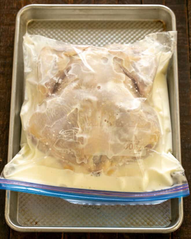 Buttermilk and whole chicken in a Ziploc bag.