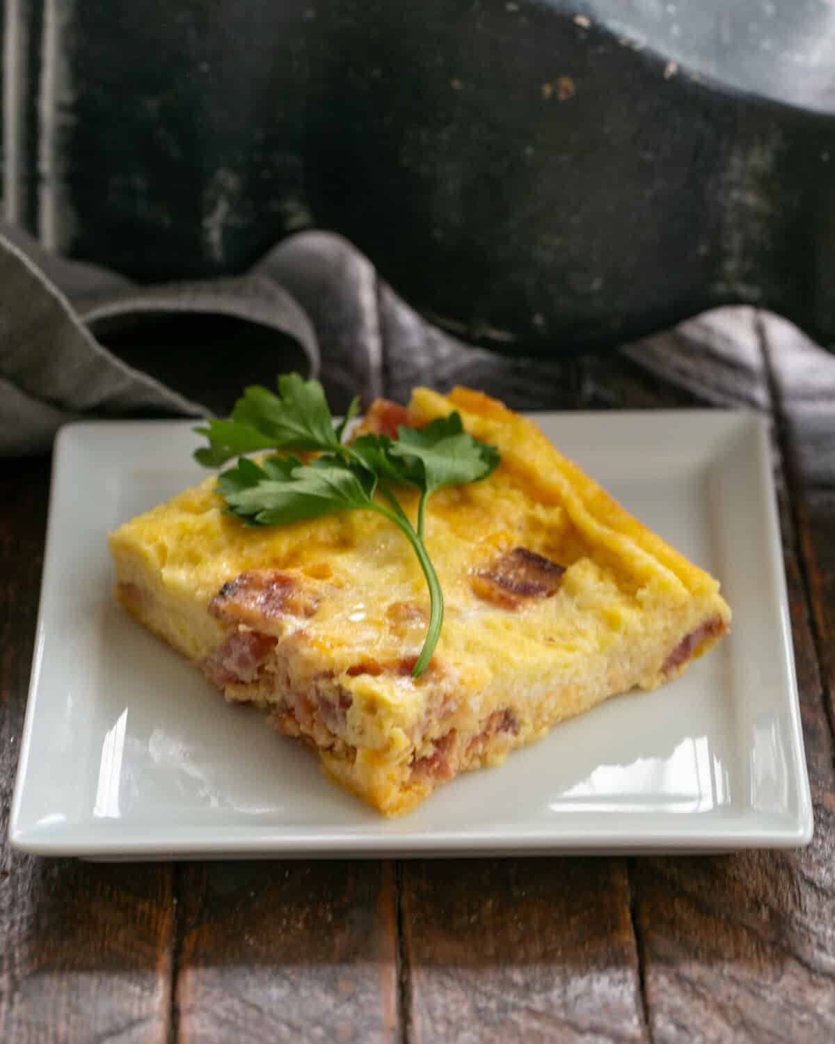 Slice of Egg Casserole on a square white plate.