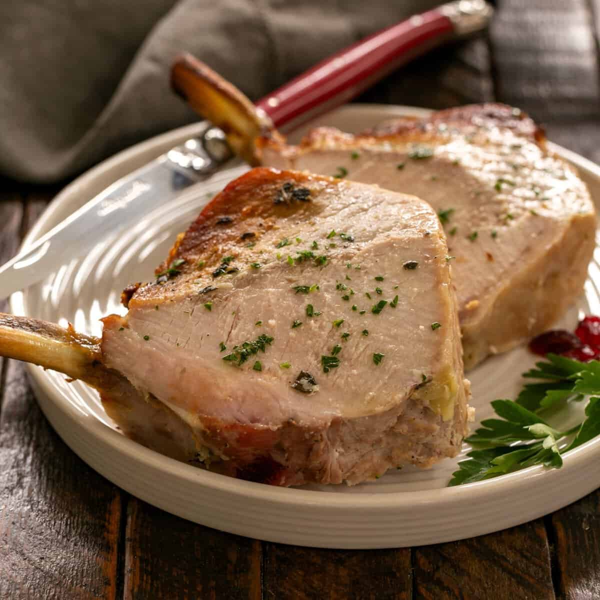 2 slices of a crown roast of pork on a round white plate.